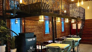 A restaurant with brick walls, hanging light bulbs, and a black metal railing. - Beautifully restored early-1900s Church. In Historic District + Pet Friendly (Tarpon Springs)