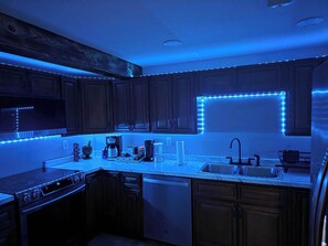 Une cuisine avec des meubles en bois foncé, un plan de travail en marbre et un éclairage à DEL sous les meubles.