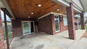 Ein überdachter Patio-Bereich mit Betonboden, Backsteinwänden und Holzbalkendecke.