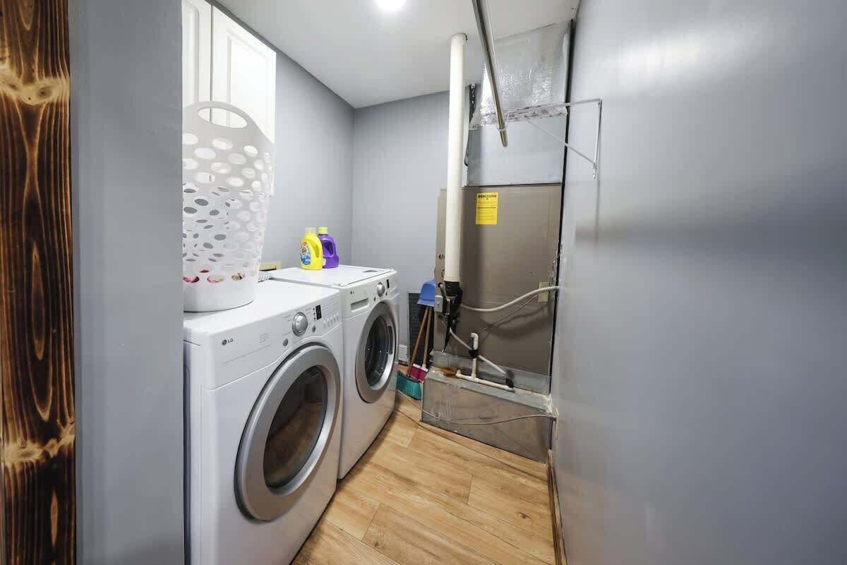 Un espace buanderie comprenant un lave-linge, un étendoir et une armoire métallique.