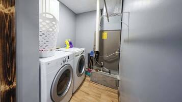 Un espace buanderie comprenant un lave-linge, un étendoir et une armoire métallique.