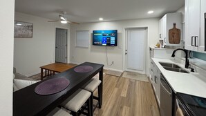 Een moderne keuken met een eethoek, een aan de muur bevestigde televisie en een plafondventilator.