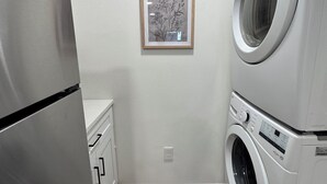 Een kleine wasruimte met een wasmachine, droger en een koelkast.