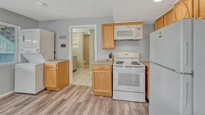 A compact kitchen with a washer, dryer, microwave, stove, and refrigerator. - Delightful 1-bedroom apartment in Castle Rock - close to the Hospital (Castle Rock)