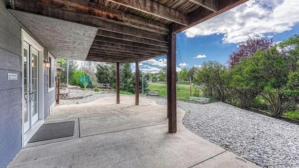 A covered outdoor area with a concrete floor, metal beams, and a view of a landscaped garden and distant mountains. - Delightful 1-bedroom apartment in Castle Rock - close to the Hospital (Castle Rock)