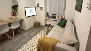 Un espacio habitable moderno y funcional con cama, escritorio y televisor.