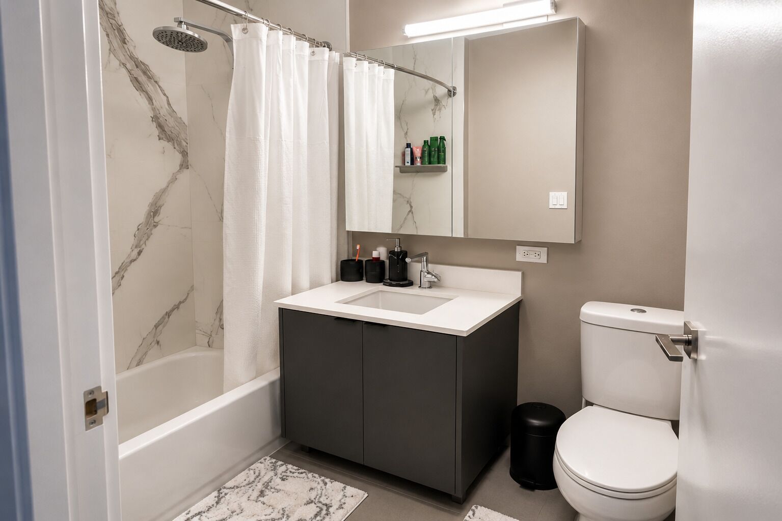 Een moderne badkamer met douche, toilet en wastafel.