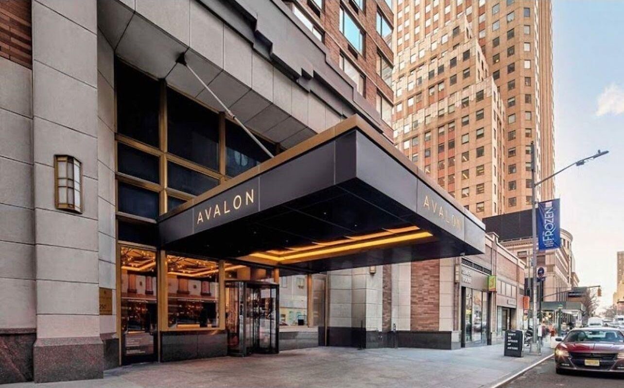 A hotel entrance with a modern design, featuring a prominent awning and large windows.