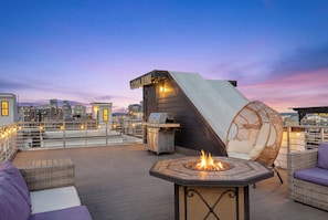 A rooftop terrace with a fire pit, wicker furniture, and a grill. - 24 beds • Mins to South 12 & Broadway • Rooftop Views (Nashville)