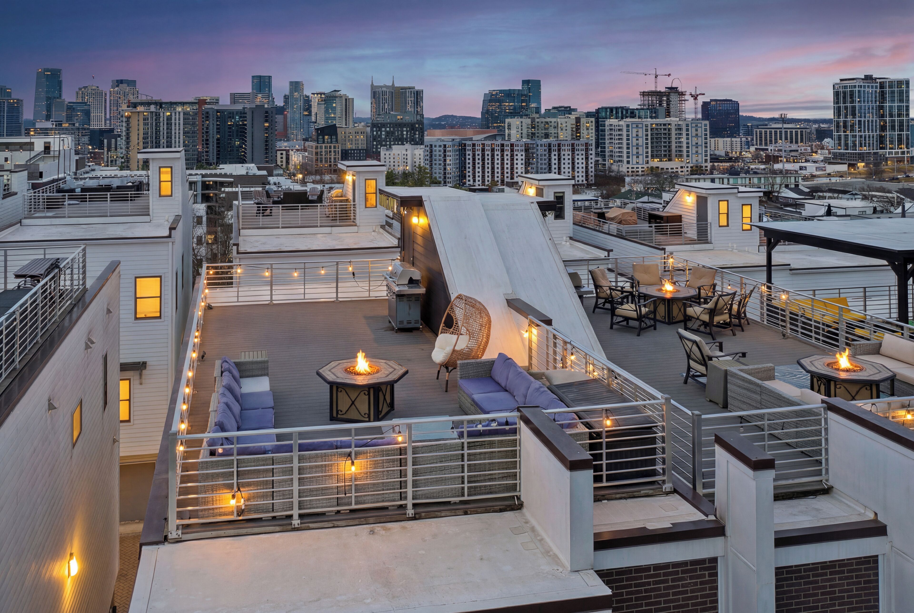 A rooftop terrace with outdoor seating, a fire pit, and a city skyline view.