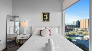 A hotel room with a large bed, a bedside table with a lamp, a mirror, and a city view. - Premium Stay 2mins to PHX Convention Ctr (Phoenix)
