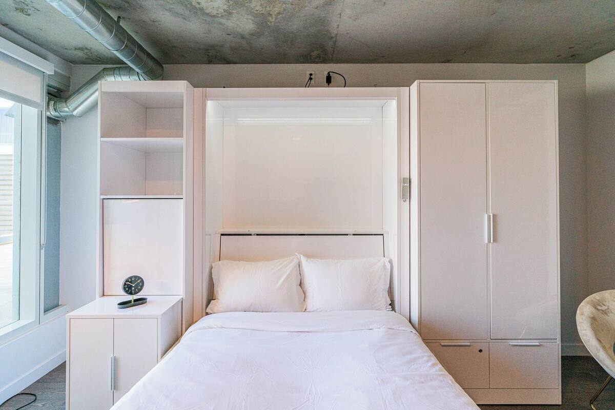 Un dormitorio con cama, armario y mesita de noche.