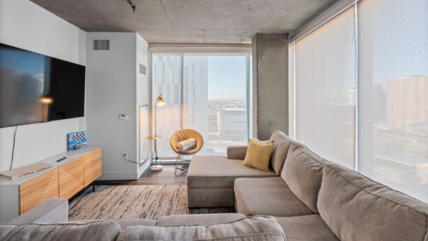 A modern living room with a large flat-screen TV, a sofa, a wooden cabinet, and a chair. - Premium Stay 2mins to PHX Convention Ctr (Phoenix)