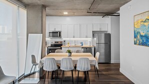 A modern kitchen with white cabinets, stainless steel appliances, and a dining area with a table and chairs. - Premium Stay 2mins to PHX Convention Ctr (Phoenix)