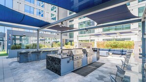 An outdoor patio with a barbecue grill, seating area, and a view of the building's exterior. - Premium Stay 2mins to PHX Convention Ctr (Phoenix)