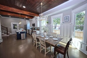 A spacious kitchen with a central island, white cabinetry, and a dining area with a wooden table and chairs. - Coastal Cove-Near Beach with a Game room (Galveston)