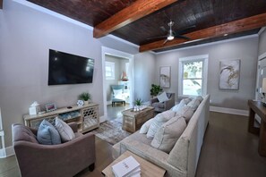A living room with a large flat-screen TV, a sofa, a coffee table, and a wooden cabinet. - Coastal Cove-Near Beach with a Game room (Galveston)