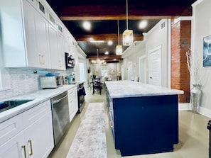 Una cocina moderna con armarios blancos, una isla central e iluminación colgante.