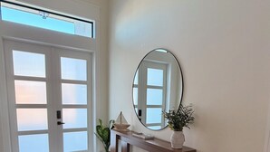 A spacious room with a large mirror, a wooden console table, a potted plant, and a sliding glass door.