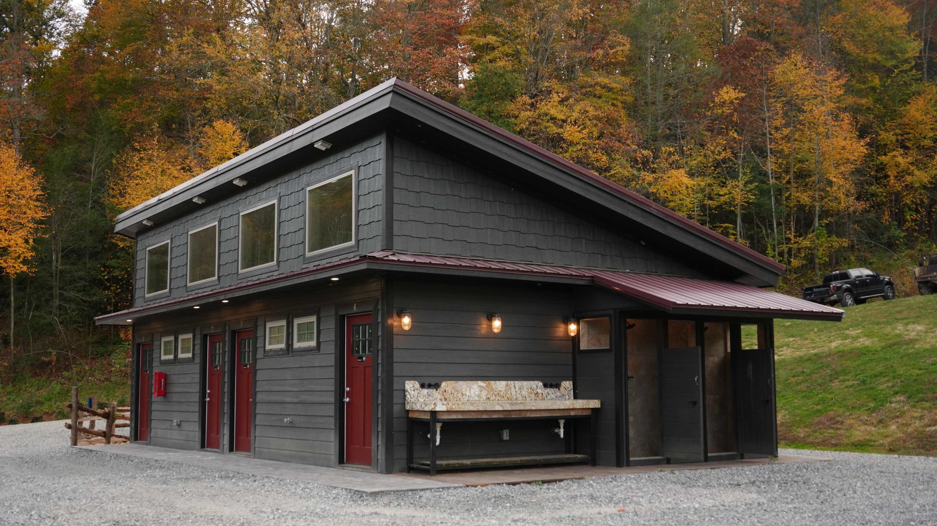 A two-story lodge with a covered porch, multiple doors, and a stone bench.