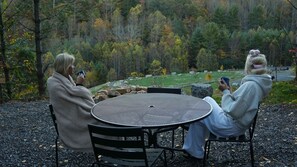 Two people seated at a round table outdoors with a forest view.