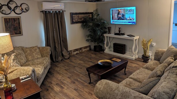 Una sala de estar con televisión, dos sofás, una mesa de centro, chimenea y una planta.