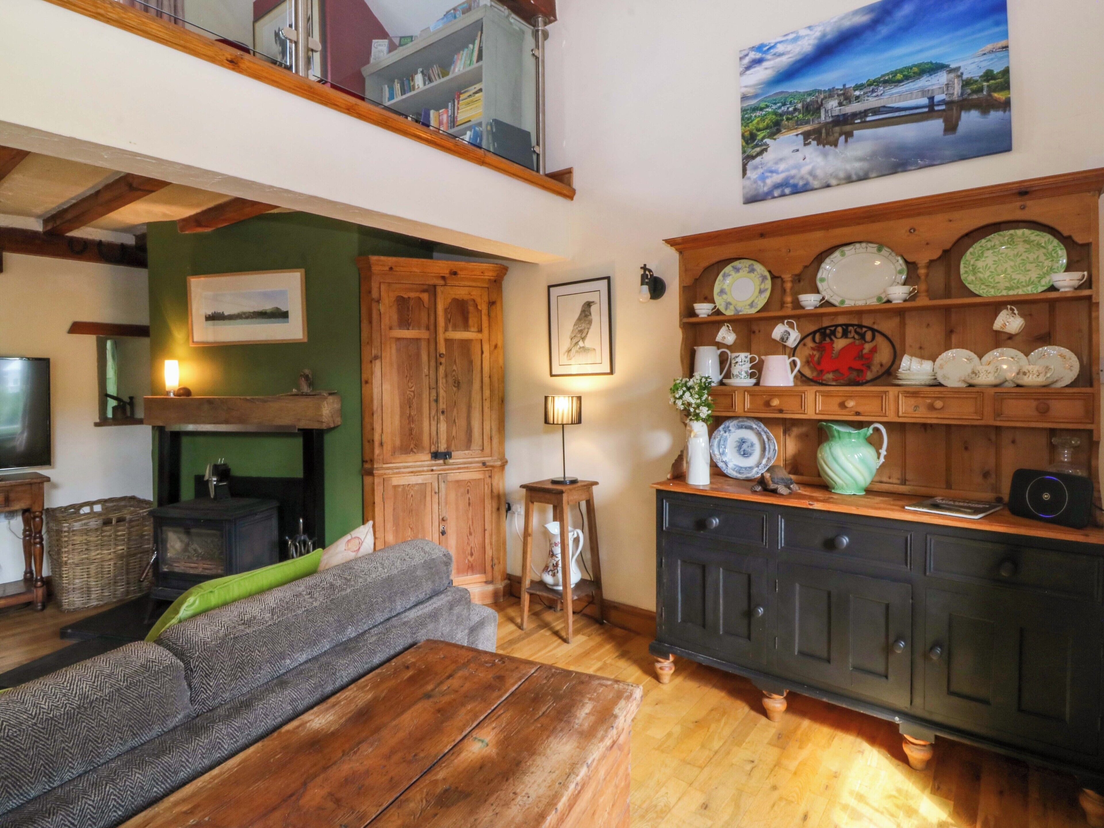 A cozy living room with a fireplace, a television, a sofa, and a wooden cabinet with dishes.