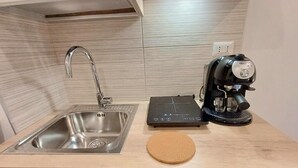 A kitchen with a stainless steel sink, a coffee maker, and a cork mat on the countertop. - PRINCE APARTMENT STUDIO (Napoli)