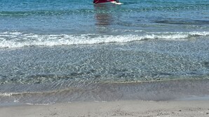 A beach with clear water and a person windsurfing. - Beautiful 4-bedroom villa,incredible view on the Gulf of Cagliari Sardinia Italy (Quartu Sant'Elena)