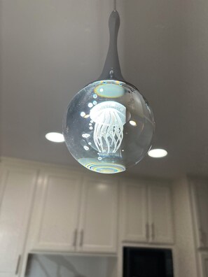 Luminária pendente com cúpula de vidro esférica e design que remete a uma água-viva.