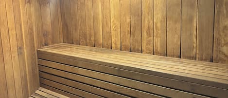 Un sauna avec des bancs en bois et un plancher incliné.