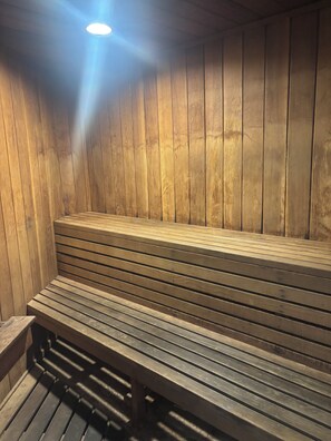Eine Sauna mit Holzbänken und leicht abfallendem Boden.