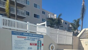 Ein Poolbereich mit einem Schild, das Schwimm- und Spa-Bestimmungen, einschließlich Rettungsschwimmerpflicht und Personenbegrenzung, detailliert beschreibt.