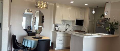 Una cocina moderna con armarios blancos, una isla central y un comedor con una mesa y sillas.
