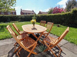 A round wooden table with chairs, a vase of flowers, and a garden setting. - Seashells at Runswick Lodge (Saltburn-by-the-Sea)
