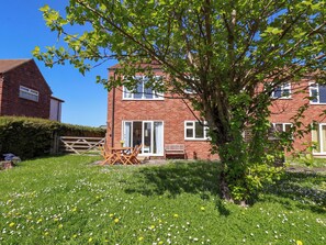 A two-story brick house with a garden, a wooden gate, and a bench. - Seashells at Runswick Lodge (Saltburn-by-the-Sea)