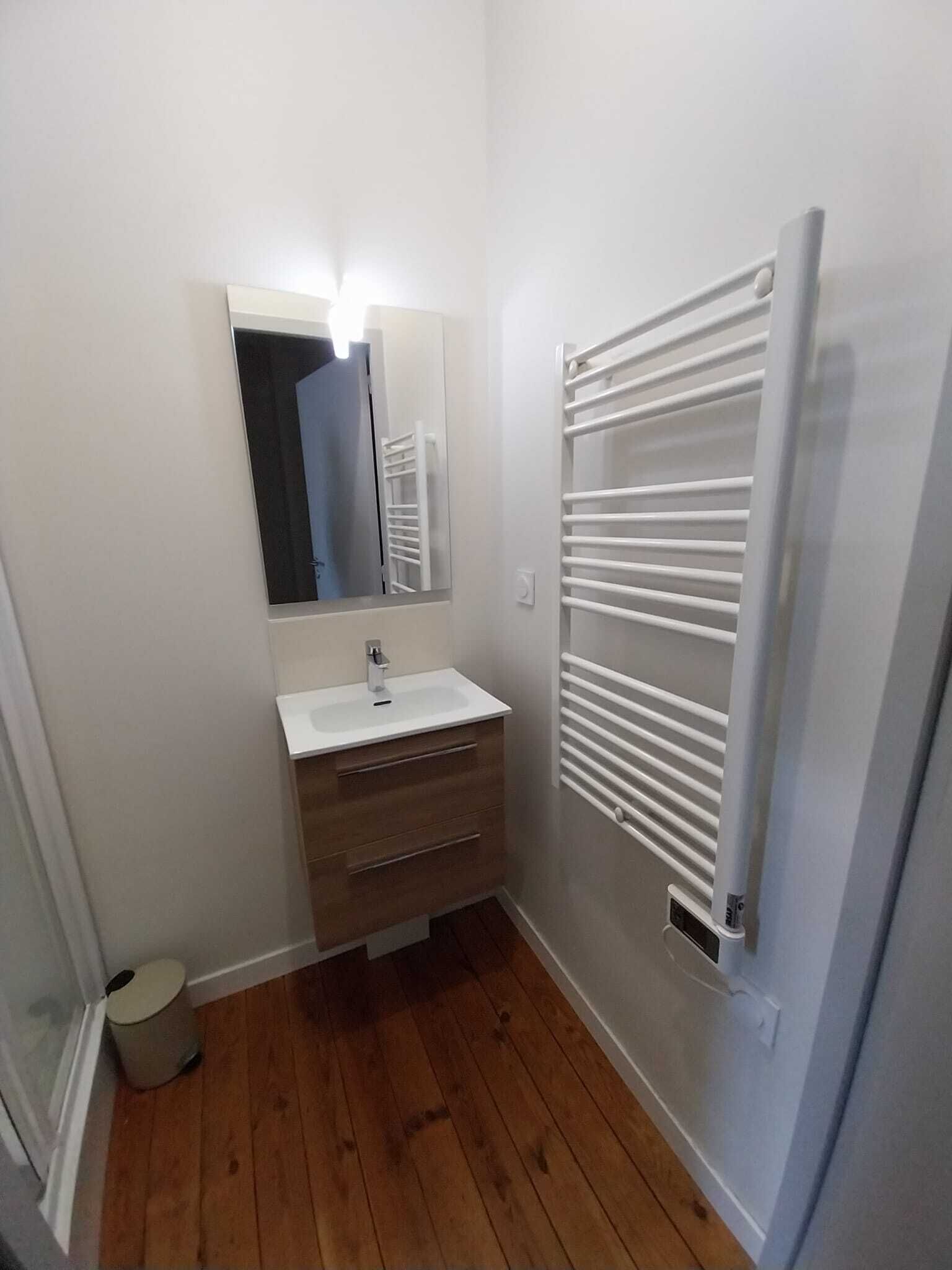 A bathroom with a white sink, mirror, and towel rack.