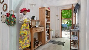 A room with a mannequin, wooden furniture, a bookshelf, and a door leading outside. - Verte Printanière Guest Room – Upstairs with Shared Terrace & Garden, Wi-Fi (Saint-Lyphard)