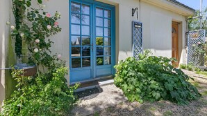 Un immeuble avec une porte bleue, le numéro 23, et un petit porche agrémenté de plantes.