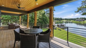 Un espace extérieur abrité, doté d’une table et de chaises, offrant une vue sur un plan d’eau et un terrain de golf.