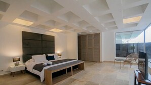A modern bedroom with a large bed, bedside tables, a bench, a TV, and a sliding door closet. - Clock Tower PH · PH in the historic center (Cartagena)