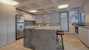 A modern kitchen with a marble island, stainless steel appliances, and a large window. - Clock Tower PH · PH in the historic center (Cartagena)
