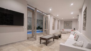 Un'ampia zona giorno con una grande TV a schermo piatto, una piscina e un moderno divano.