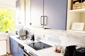 Una cocina moderna con estufa integrada, un lavamanos y una cafetera.