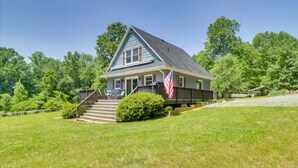 A house with a front porch, a flag, and a staircase leading to the entrance. - Lakefront 3-bedroom chalet with private dock (Louisa)