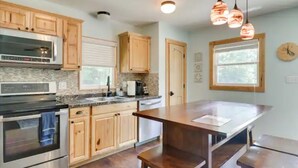 A kitchen with wooden cabinets, stainless steel appliances, a granite countertop, and pendant lighting. - Lakefront 3-bedroom chalet with private dock (Louisa)
