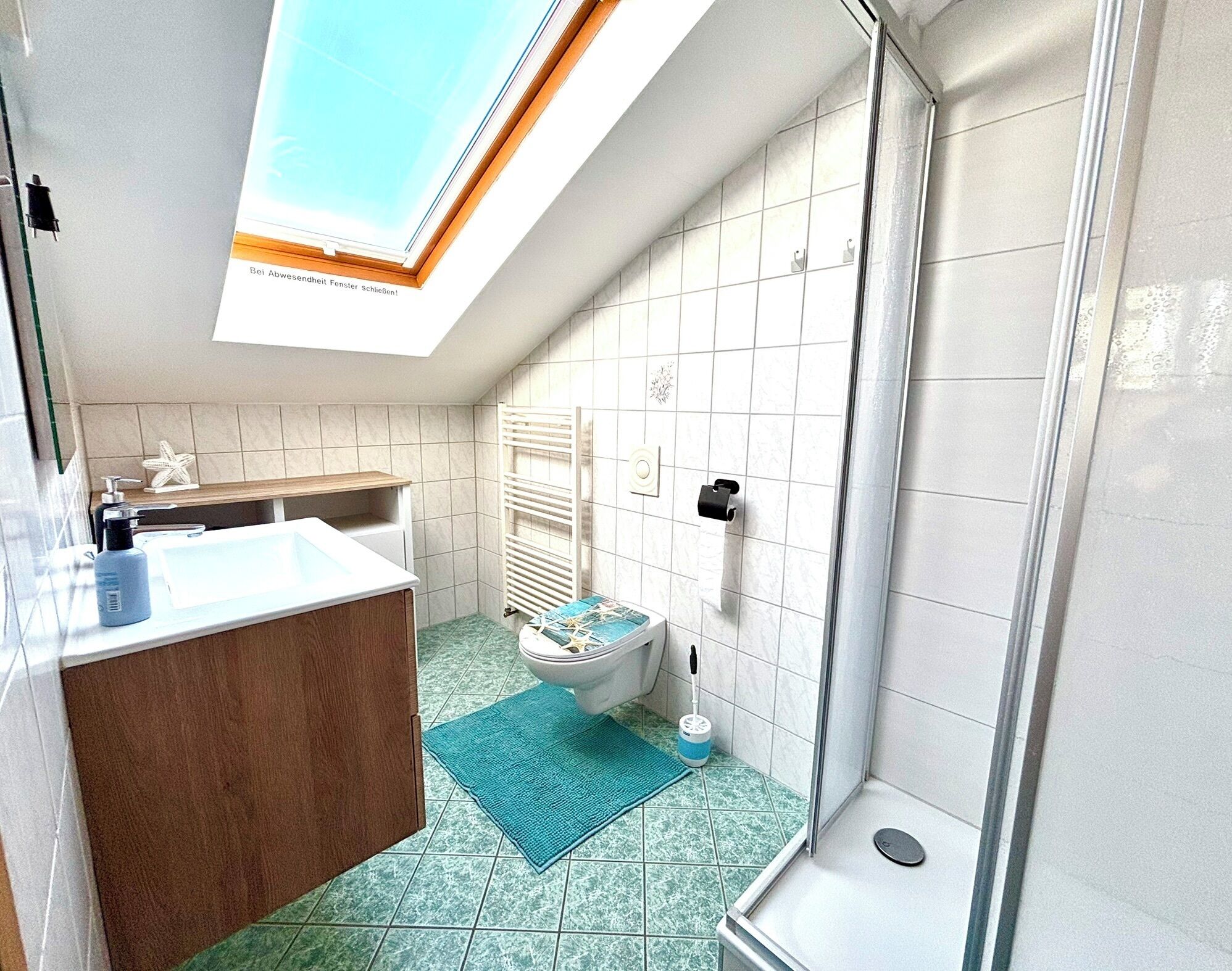 Un bagno moderno con finestra sul tetto, doccia, WC e lavandino.