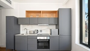 Une cuisine moderne avec des meubles gris, un four encastré et une fenêtre donnant sur la ville.