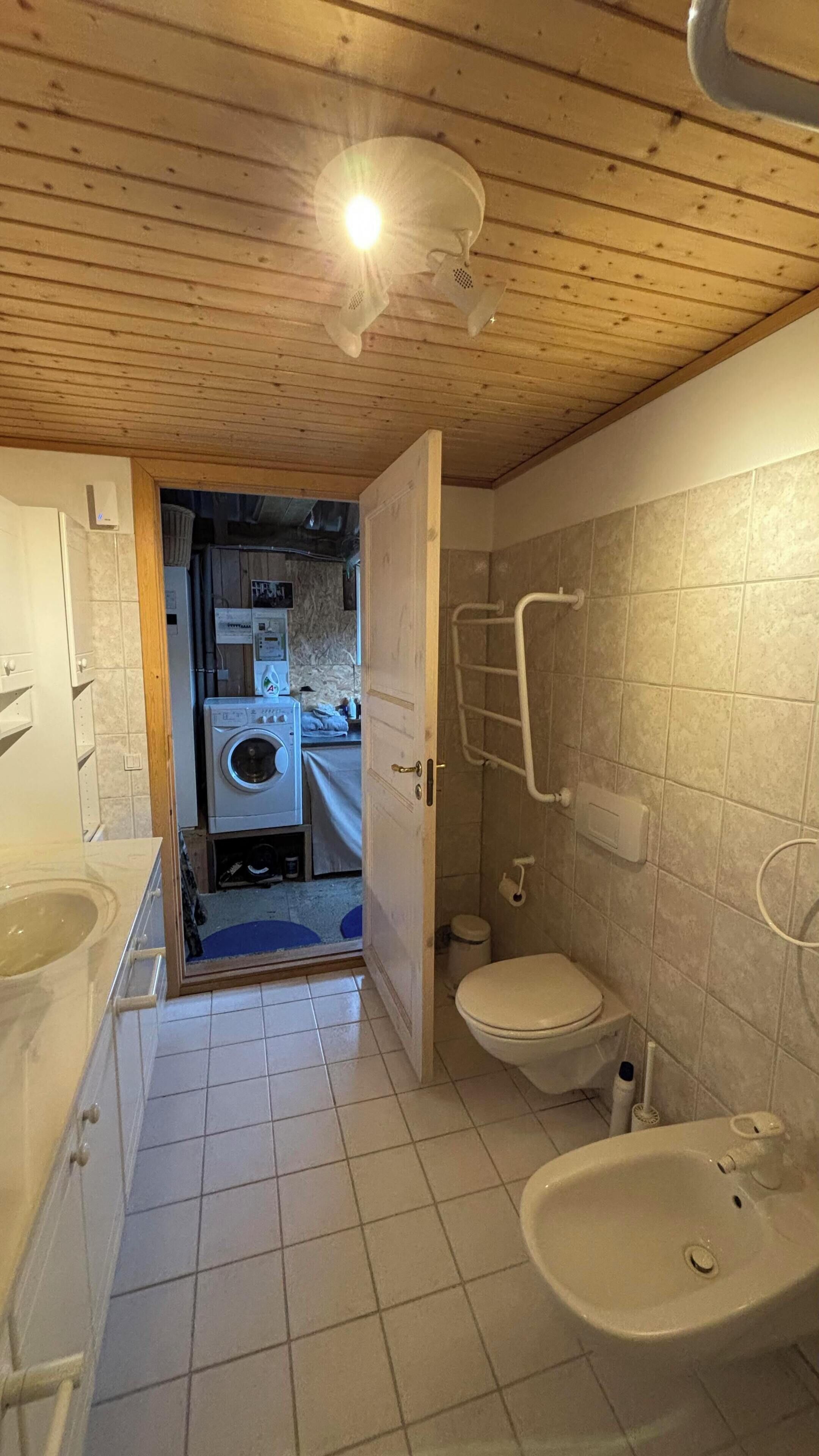 A compact bathroom with a toilet, sink, and shower area.