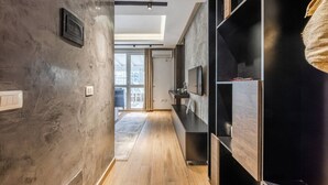 A hallway with a wooden floor, a TV mounted on the wall, and a door leading to an outdoor area. - Vista Mare Horizon | Patio with Amazing Seaview by PikHost (Vlorë)